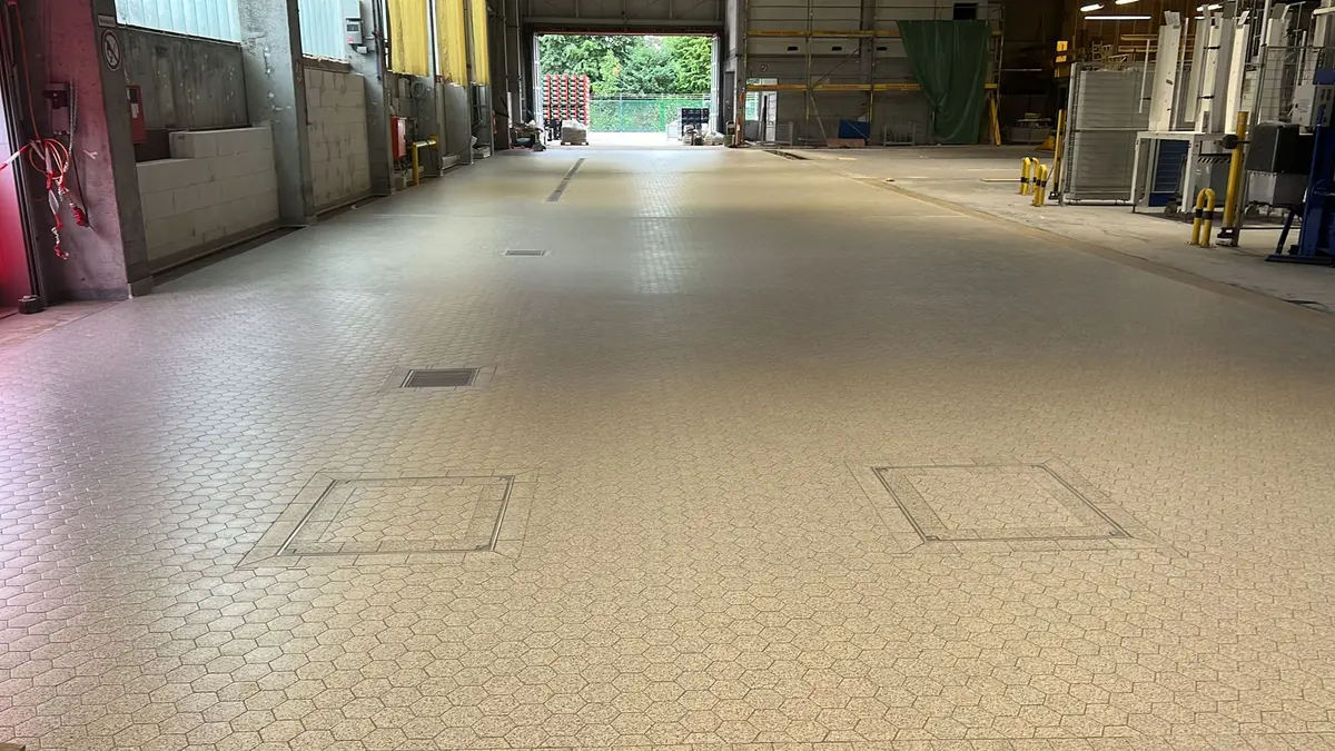 Industrial tiled floor equipped with drainage channels, floor drains, and inspection hatches